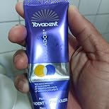Tubo roxo da TOYADENT Ultravioleta na mão de um cliente